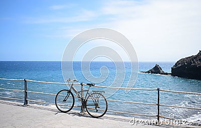 Bicycle leaning against the path fence near the sea in Golf del Sur. Stock Photo