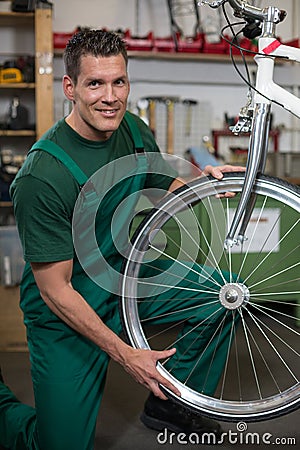 Bicycle mechanic repairing wheel on bike in a workshop Stock Photo