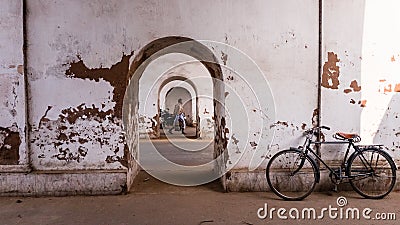 A bicycle parked beside the walls of an old, arched, faded tunnel with diminishing Editorial Stock Photo