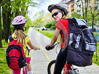 Bicycle path with children. Girls wearing helmet with rucksack ciclyng ride. Stock Photo