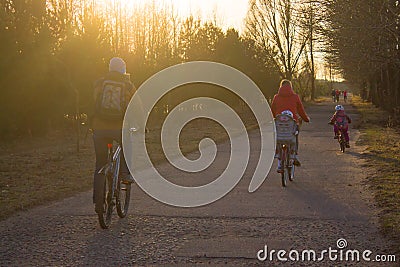 Bicycle path, people ride their whole family on bicycles, a sporty and healthy lifestyle and the setting sun Stock Photo