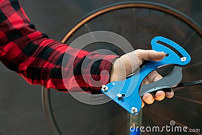 Bicycle repair. In the mechanic's hand is a professional tool for repairing wheels and tensioning spokes. Stock Photo