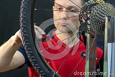 Bicycle repair. Rear wheel and tire closeup. Mechanic repairing spokes of the rear wheel of a mountain bike. Bike mechanic in the Stock Photo