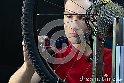 Bicycle repair. Rear wheel and tire closeup. Mechanic repairing spokes of the rear wheel of a mountain bike. Bike mechanic in the Stock Photo