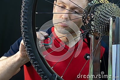 Bicycle repair. Rear wheel and tire closeup. Mechanic repairing spokes of the rear wheel of a mountain bike. Bike mechanic in the Stock Photo