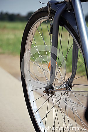 Bicycle wheel with road and greenery in the background. Stock Photo