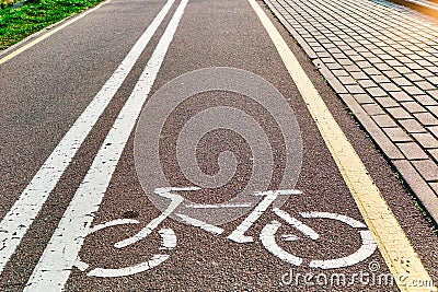 Bicycle white and yellow lanes sign and image of a bicycle with sun rays on road surface Stock Photo