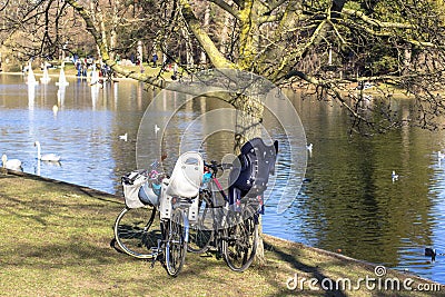 Bicycles in the park by the pond in which birds float. People on the other side launch model sailboats Stock Photo