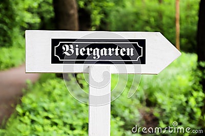 Biergarten Beer Garden in German white wood arrow direction sign with traditional German writing font. Sign in open air Stock Photo