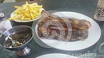 Bife de tira, Montevideu Market, Uruguay. Typical Barbecue with french fries and chimichurri sauce Stock Photo