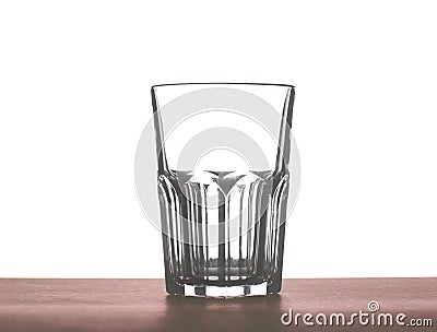A big beautiful empty glass for water, juice or milk on a dark brown wooden table, isolated on a white background. Stock Photo