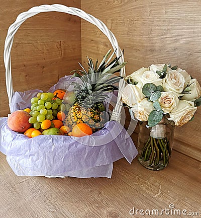 Big beautiful white basket of fruits, pineapple, peaches, tangerines, grapes, mangoes, apples, oranges, bananas Stock Photo