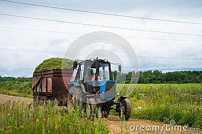 Big blue tractor rides past the field Stock Photo