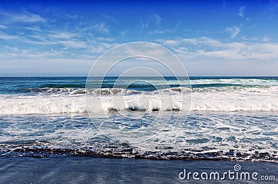 Big breaking Ocean wave on a black sandy beach on Pacific ocean. Stock Photo