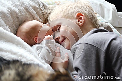 Big Brother Hugging Newborn Baby with Love Stock Photo