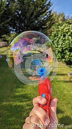 A big bubble made by a red bubble gun in the garden Stock Photo