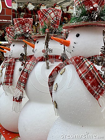 Big christmas snowman with red scarf and hat standing at the hat`s retail shop. Group of snowmen Stock Photo