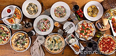 Big dinner table with italian food, pizzas and pastas Stock Photo