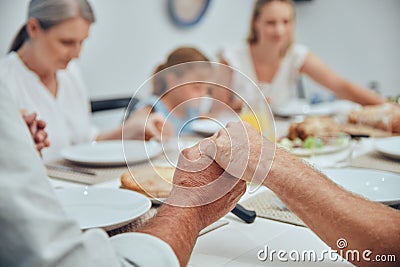 Big family, holding hands and pray before food with love, care and god worship before eating. Buffet, prayer and Stock Photo