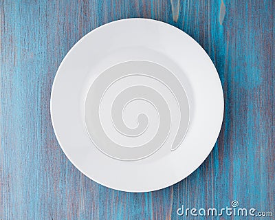 Big flat empty white plate on blue wooden table, top view Stock Photo