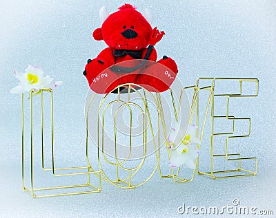 Big gold letters LOVE on silver background and Teddy davil Stock Photo