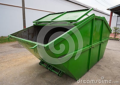 Big green dumpster garbage truck on the road in the factory, Side view Stock Photo