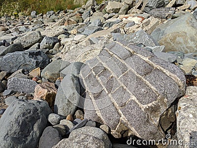 Big grey brick boulder block wall on a rocky beach waterfront Stock Photo