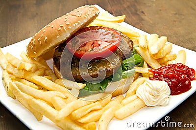 Big hamburger, French fries and vegetables Stock Photo