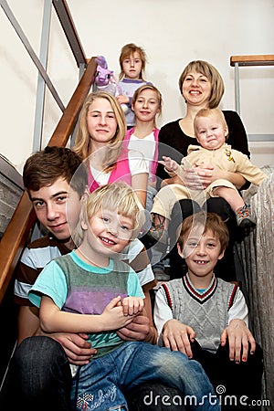 Big happy family sitting on the stairs at home. Stock Photo