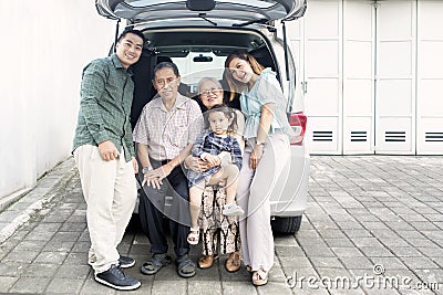Big happy family sitting on the trunk of their car Stock Photo