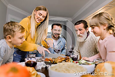 Big happy family with two kids eating Thanksgiving dinner. Roasted turkey on dining table. Parents and children having Stock Photo