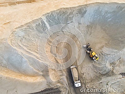 Big heavy wheel loader loading sand into dump truck in sand pit. Heavy industrial machinery concept Stock Photo