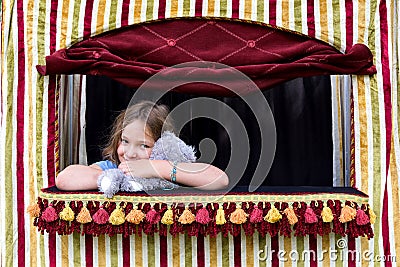 Little girl squeezing stuffed animal puppet in small puppet theater Stock Photo