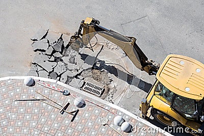 Big jackhammer drill drilling road.Heavy machinery crushing asphalt for stormwater drain repair Stock Photo