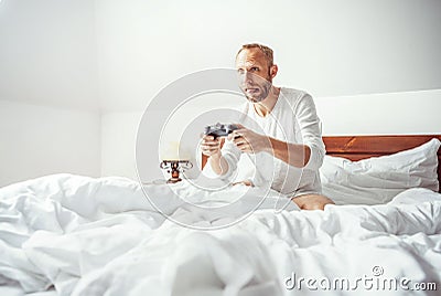 Big little boy: adult man waked up and plays PC games sitting in Stock Photo