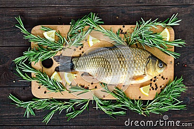 Big live carp crucian on a cutting board with rosemary branches. Stock Photo