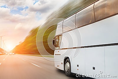 Big luxury comfortable tourist bus driving through highway on bright sunny day. Blurred motion road. Travel and coach Stock Photo