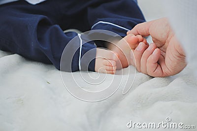 big manÐ¢s hand touches the little fingers of a child, close-up, the baby is sitting with bare feet, photo on a white background Stock Photo