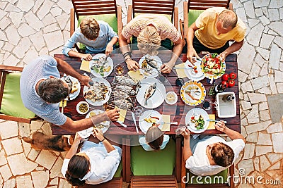 Big miltigeneration family dinner in process. Top view vertical image on table with food and hands Stock Photo