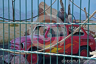 A big monkey is sitting by the car in a cage, summer Editorial Stock Photo