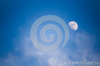 A big moon in the afternoon against a blue sky with clouds Stock Photo