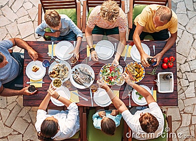 Big multigenerational family dinner in process. Top view image on table with food and hands. Food consumption and Stock Photo