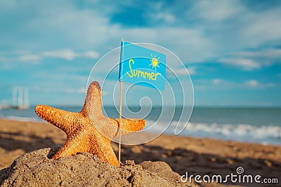 Big orange starfish with flag at the seashore Stock Photo