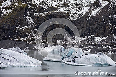Big pieces of freshwater ice in the frozen lake surrounded by rocky mountains Stock Photo
