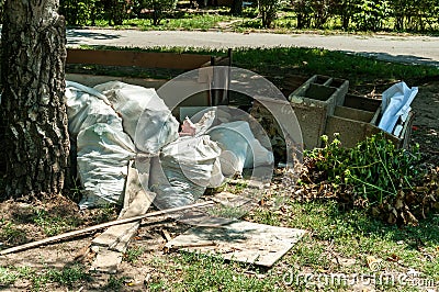 Big pile or stack of garbage and junk dumped on the grass near street polluting the city with smell and litter Stock Photo