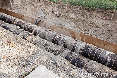 Big pipes in hole in the ground covered with dirt Stock Photo