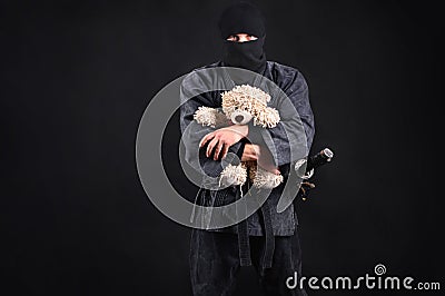 Big and powerful ninja samurai holding a teddy bear. Stock Photo