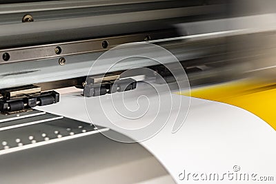 Big professional printer, processing a large scale glossy sheet of yellow paper rolls for color sampling. Stock Photo