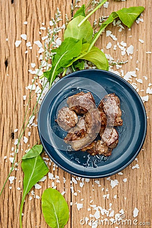 Medium Rare Fried Diced Marinated Beef on Blue Ceramic Plate on Wood Panel with Sea Salt and Vegetable Decorated Stock Photo