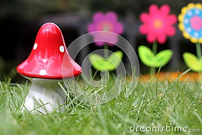 Big red mushroom toy with colorful artificial flowers in background Stock Photo